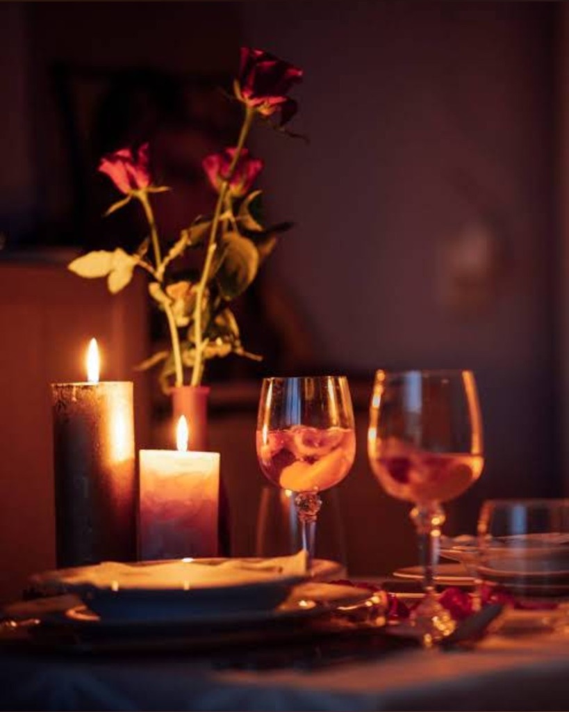 Candle light dinner setup with roses and wine glasses