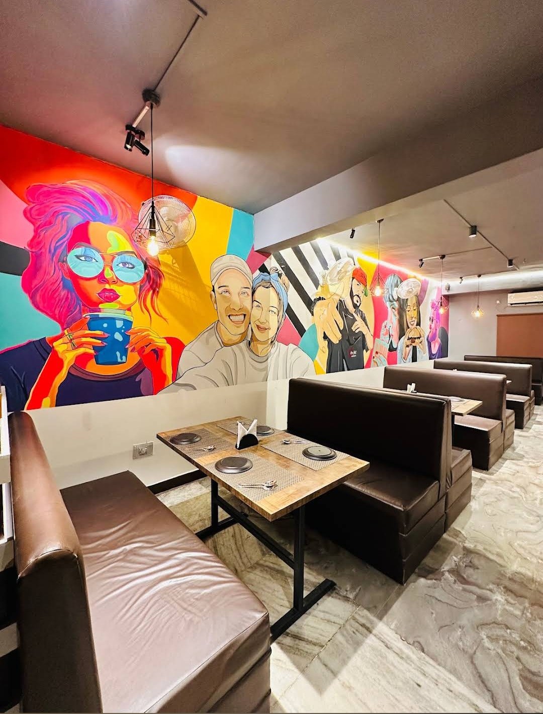 Indoor lounge with colorful art mural and brown leather booth seating